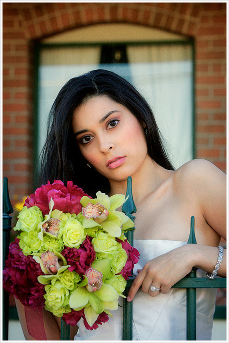 A bride with a color bouquet standing in front of a gate